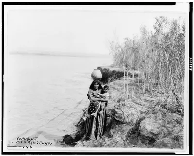 [Mohave woman carrying water on her head and holding child], Arizona, 1903