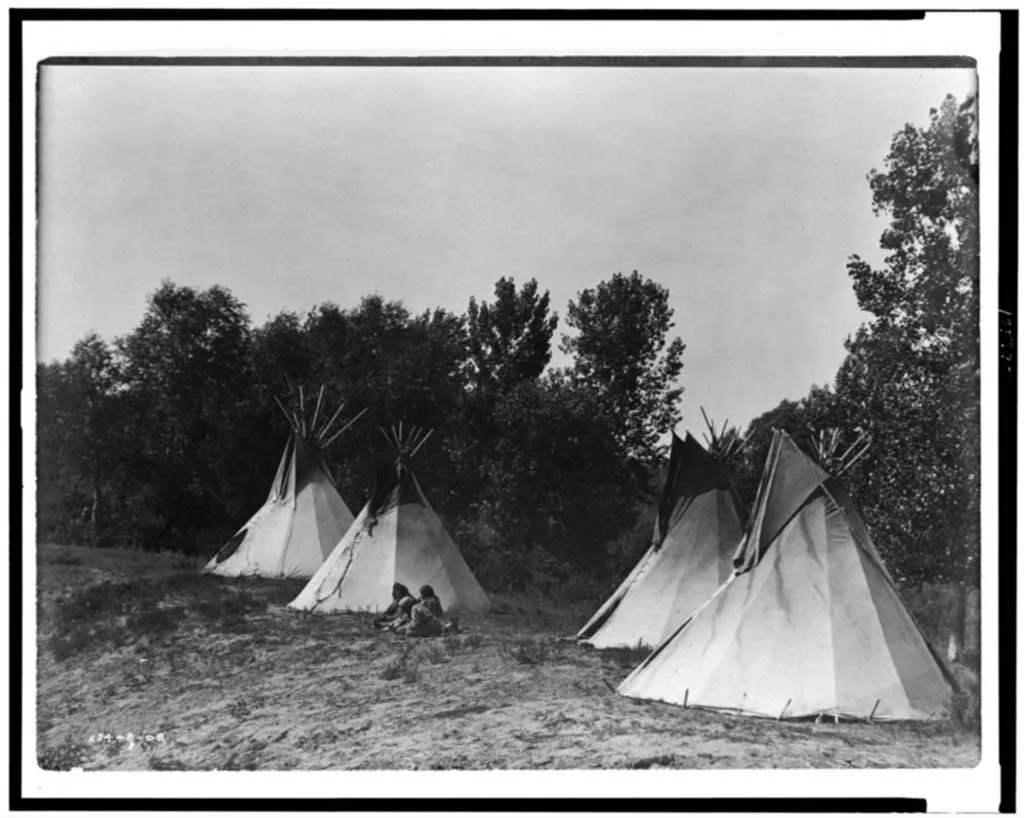 [An Assiniboin camp containing four tepees with Indians seated on…, 1908